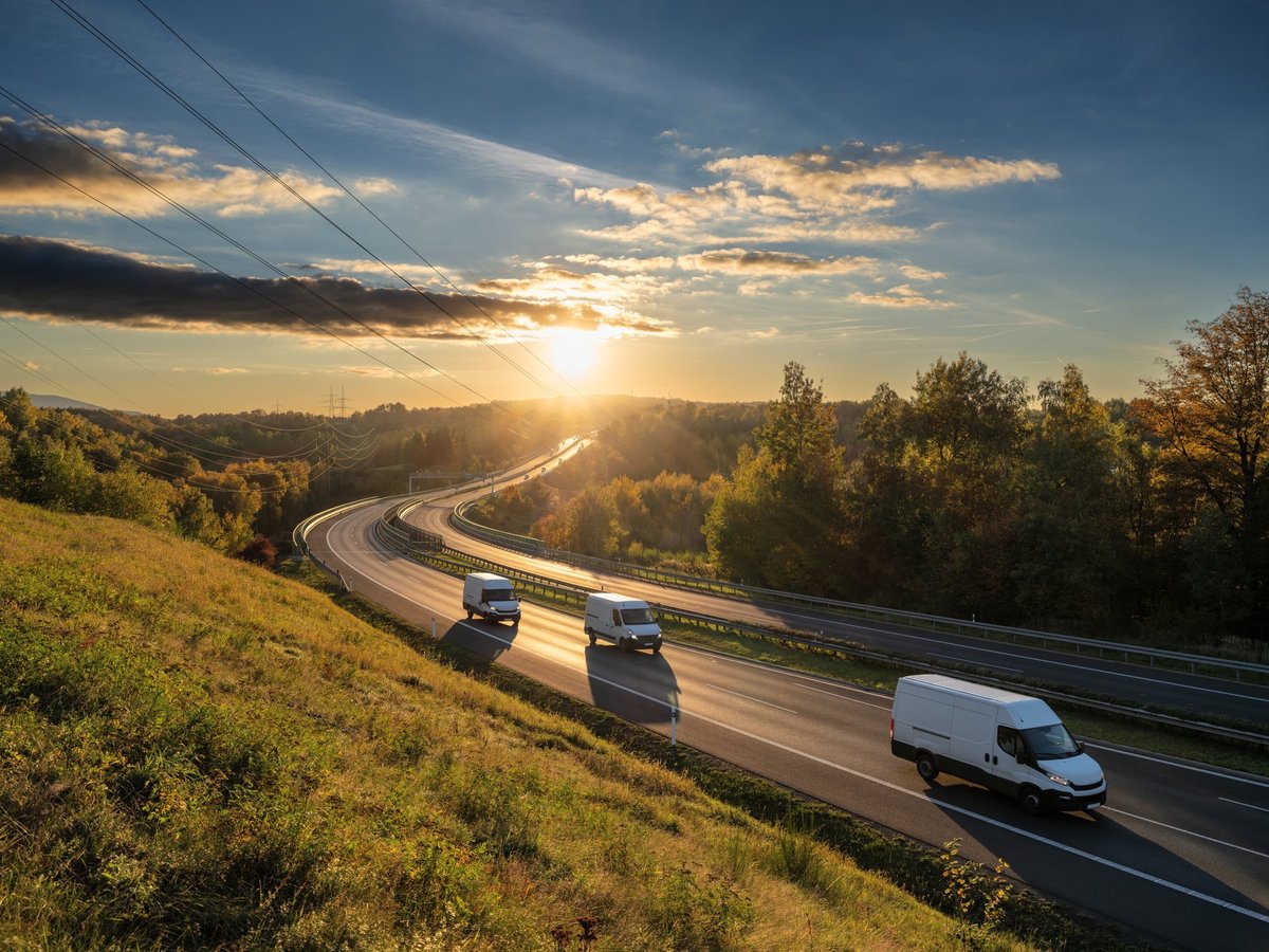 High-roof cargo van traveling a regional highway at dusk